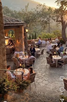 an outdoor dining area with tables, chairs and people sitting at the tables in it