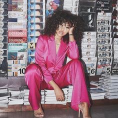 a woman sitting on top of a pile of books in front of a stack of magazines