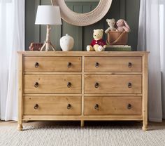 a wooden dresser with stuffed animals on top and a hammock hanging above it