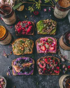 several different types of breads with fruit on them next to honey jars and flowers