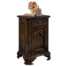 an ornate wooden cabinet with flowers on top