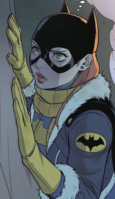 a woman dressed as batgirl holding her hand up