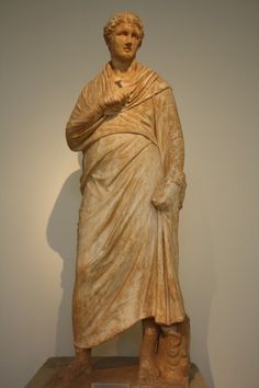 a statue of a man with a cape on his head and hands in his pockets