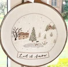 a white embroidered snow globe hanging on a window sill in front of a house