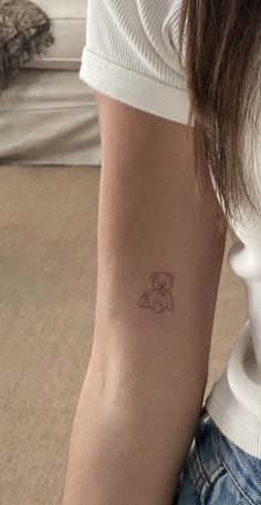 a woman with a small tattoo on her arm that has a teddy bear in the middle