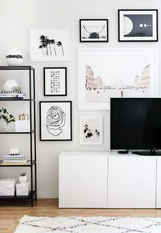 a living room with white furniture and pictures on the wall above it, along with a flat screen tv