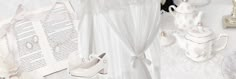 there is a white wedding dress and shoes on the table next to an open book