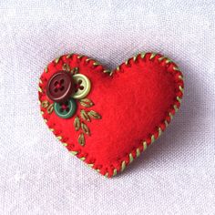 a red heart shaped brooch with buttons on it