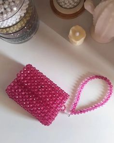 a pink purse sitting on top of a table next to other beads and accessories,