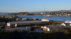 an aerial view of houses and water in the foreground with mountains in the background