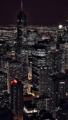 an aerial view of the city at night with skyscrapers lit up in red and white