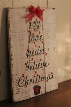 a wooden sign that says, joy love peace and believe christmas with a red bow