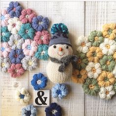 crocheted snowman and flowers on white wooden background with number 8 written in black