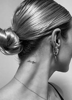 a woman with a tattoo on her neck and behind her ear is looking to the side