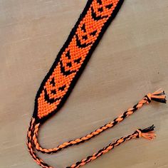 an orange and black beaded lanyard with tassels