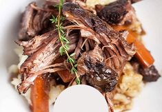 a close up of a plate of food with meat and carrots on it,