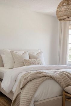 a bed with white linens and pillows in a bedroom next to a large window