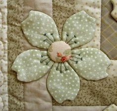 a close up of a patchwork quilt with a flower on the center and two birds in the background