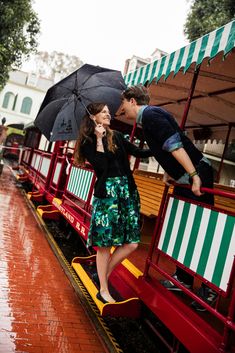 a man and woman kissing while standing on a miniature train