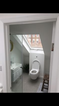 a white toilet sitting inside of a bathroom next to a window