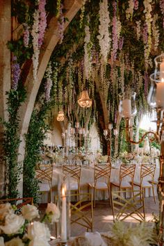 an elegant wedding reception with flowers and chandeliers hanging from the ceiling, surrounded by greenery