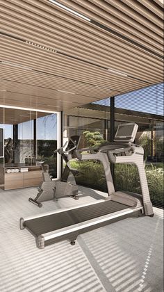 an exercise room with treadmills and desk in the center, surrounded by glass walls