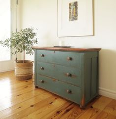 an old dresser is painted green and has a potted plant on top of it