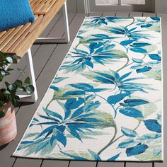 a blue and green rug on the floor next to a bench with a plant in it