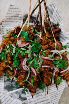 several skewers filled with meat and veggies on top of newspaper