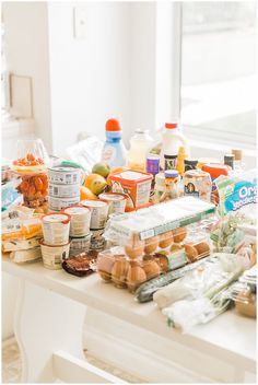 an assortment of food is sitting on a table in front of a window with the sun shining through it