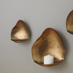 two gold leaf shaped candle holders on a wall