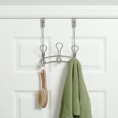 a towel and toothbrush hanging on a hook in front of a door with two hooks