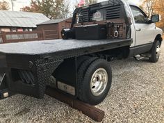 the flatbed truck is parked on gravel