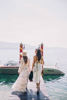 two women standing on a dock next to a boat