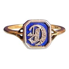 Step into the elegance of the Edwardian era with this distinguished initial ring, a testament to the refinement and artistry of the early 20th century. At its center lies a striking blue enamel panel, meticulously framed in platinum. The focal point of this exquisite piece is a platinum Gothic-style letter "D," adorned with delicate rose cut diamonds that sparkle with a timeless allure.  Crafted from 18 karat gold, this ring is a true masterpiece of design and sophistication. Measuring 8.6 mm from north to south, this ring is a small yet significant statement of elegance and personal touch. Weighing 2.3 grams and sized at 5.5, this ring is not merely a piece of jewelry but a symbol of identity and style. The intricate craftsmanship and luxurious materials make it a perfect heirloom, a cher The Edwardian Era, Gold Cocktail Ring, Gold Cocktail, Letter D, Initial Ring, Edwardian Era, Gothic Style, Garnet Rings, Rose Cut Diamond