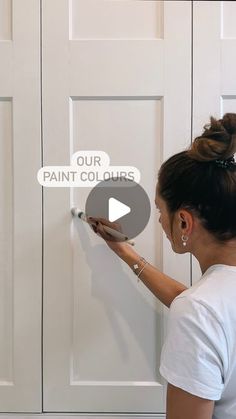 a woman is painting the door with white paint