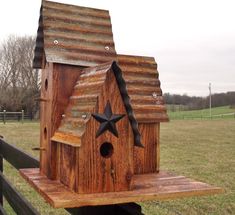 a wooden birdhouse with a star on the roof and a fence in the background