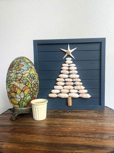 a wooden table topped with an egg next to a stained glass christmas tree