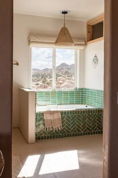 a bathroom with a green tile tub and window