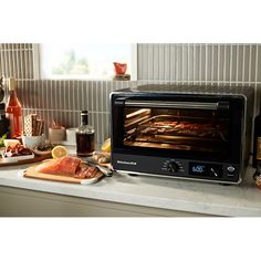 a toaster oven sitting on top of a counter next to bottles of wine and food