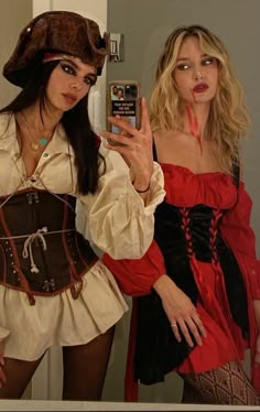 two women dressed up in pirate costumes taking a selfie with their cell phone camera