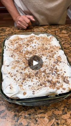 a man standing in front of a cake on top of a counter with white frosting