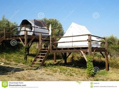 a tent set up on top of a wooden platform in the middle of an open field