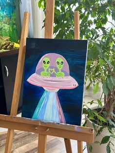 an art easel with a painting of two aliens on it