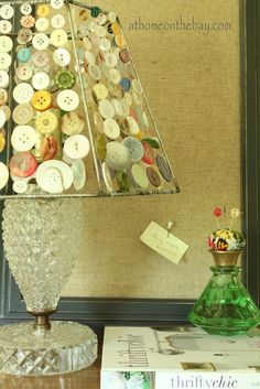 a lamp that is on top of a table next to a book and some buttons