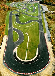 an aerial view of a race track surrounded by grass and trees in the fall season