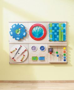 a wall mounted art piece on the side of a yellow wall with various items hanging from it