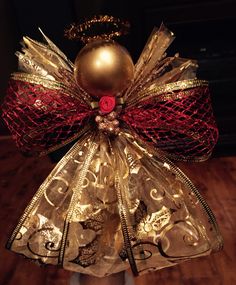 a gold and red christmas angel ornament sitting on top of a wooden table