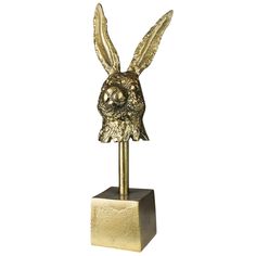 a gold statue of a rabbit head on a stand with its ears open and eyes closed