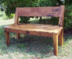 a wooden bench sitting in the grass under a tree